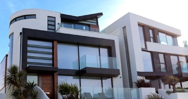 Large, modern luxury home with panoramic windows under a blue sky.