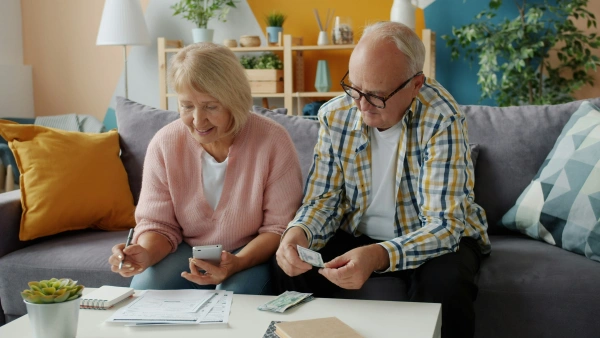 Senior couple (third age) reviewing bills and financial documents at home. Credit renegotiation and solutions for retirees.