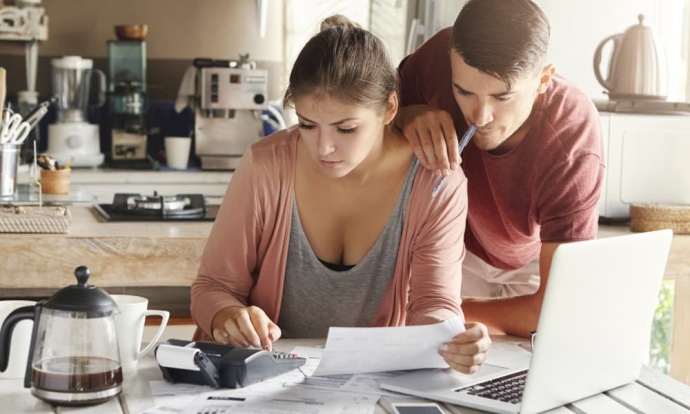 Couple in the kitchen analyzing documents on a laptop to reduce mortgage payments