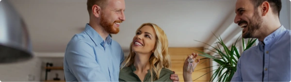 Happy couple receiving house keys from a smiling advisor